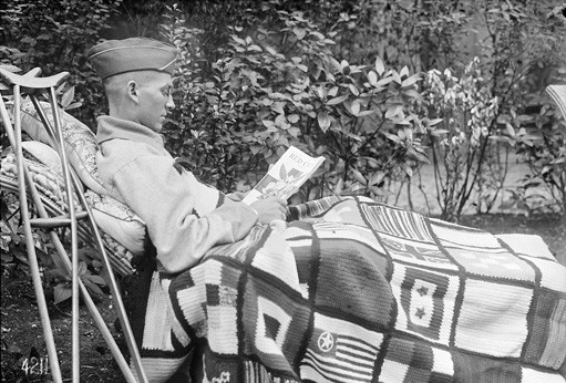 A Lieutenant at A.R.C. Military Hospital, No. 3,  Rue de Chevreuse, Paris, who has had a leg amputation, enjoys the Red Cross magazine, as well as the new robe sent by a Red Cross Chapter in America, August 1918, photographed by Lewis Wickes Hine, American National Red Cross photograph collection, Library of Congress