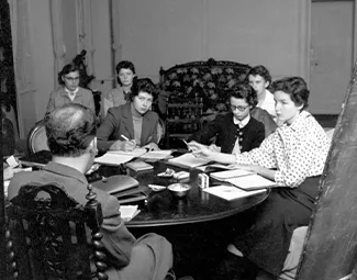 Students discussing with professor in a salon, 1950s. Photograph retrieved from U.S. National Archives & DVIDs.